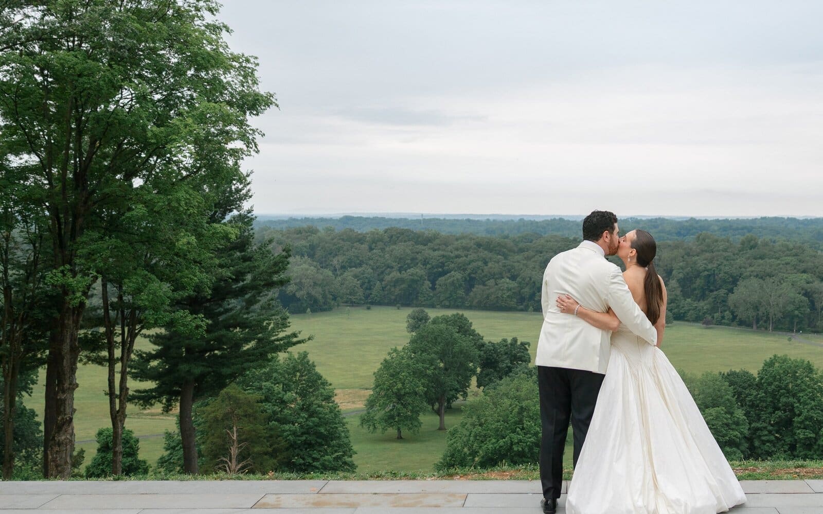Kara and Nick sharing a kiss on the terrace at Pendry Natirar with the valley behind them
